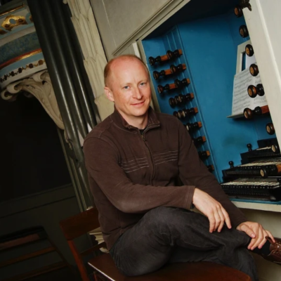 James Johnstone sat on a stool in front of harpsichord